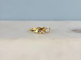 bague en or jaune ornée d'une perle et de diamants, posée sur une plaque de marbre