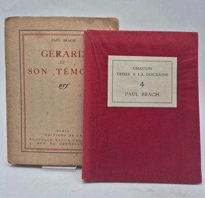 un vieux livre posé sur une table blanche à côté d'un livre rouge