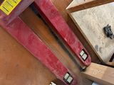 a red pipe clamp sitting on the floor next to other tools