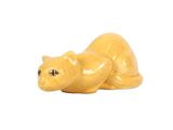 une figurine de chat jaune posée sur une surface blanche