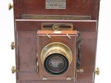 an old wooden camera sitting on top of a white surface