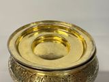 a gold bowl with a lid on a white surface