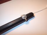 une bague en diamant posée sur un stylo, sur une surface blanche