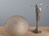a statue of a woman standing next to a ball on a table