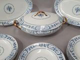 six blue and white plates with gold rims are arranged in a circle