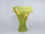 un vase vert contenant des fleurs jaunes, posé sur une surface blanche