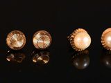 five pairs of gold and pearl rings on a black surface