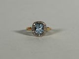 a gold ring with a blue topaz stone surrounded by diamonds