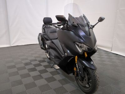 une photo d'une moto noire garée sur un sol à carreaux