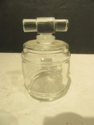 a small glass jar with a metal handle on a table