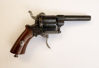 un vieux revolver avec une poignée en bois sur une surface blanche