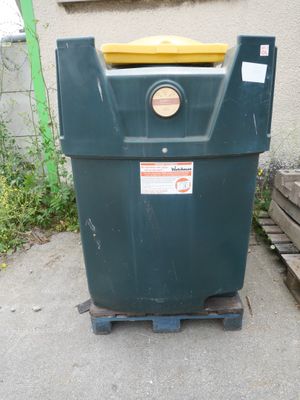 une poubelle verte avec un couvercle jaune posée sur une palette