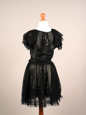 une robe noire posée sur un présentoir à mannequin, avec un collier autour du cou