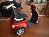 a red scooter parked in a room with a couch