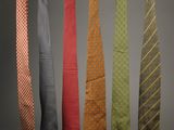four different colored ties hanging on a rack in a room