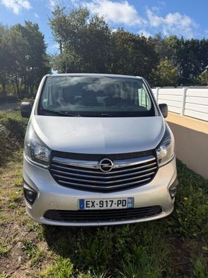 une camionnette argentée garée sur le bord de la route, près d'une clôture