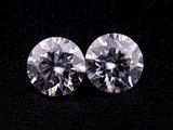 a pair of round cut diamonds on a black surface