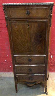 une armoire ancienne en bois avec un plateau en marbre, placée devant un mur de briques rouges