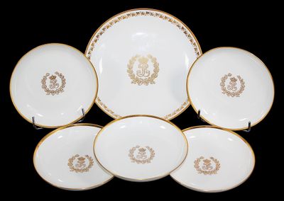 six assiettes blanches et dorées, ornées de bordures dorées sur fond noir