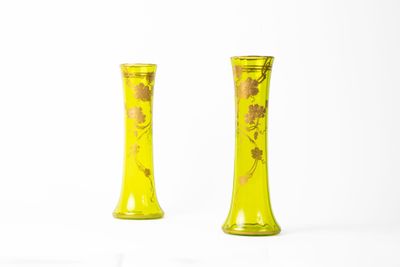 une paire de vases jaunes ornés de fleurs dorées sur fond blanc