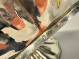 a silver vase with a painting on it sitting on a table