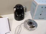 a black coffee pot sitting on top of a table next to a notepad