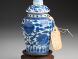 blue and white porcelain jar with lid on wooden stand with tag