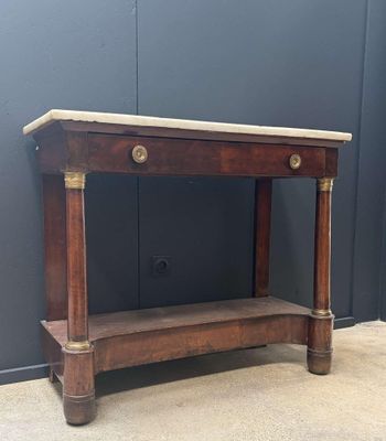 une vieille table en bois avec un plateau en marbre, posée sur un sol en béton