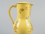 a yellow pitcher with a floral design on it