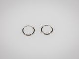 une paire de boucles d'oreilles créoles en argent sur fond blanc