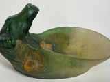 un bol vert orné d'une grenouille, posé sur un fond blanc