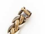 a close up of a gold and silver bracelet on a white surface