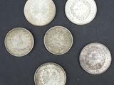 six pièces d'argent sont disposées en cercle sur une surface noire