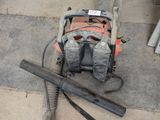 a bag and a saw on the ground next to a gas pump