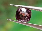 quelqu'un tient une pince dans laquelle se trouve un diamant rose