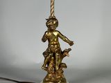 une statue en or représentant un garçon tenant une lampe, posée sur un socle en marbre