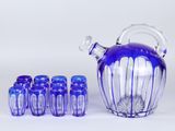 un pichet en verre violet avec six verres bleus et une cruche en verre