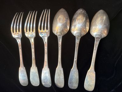 six cuillères et fourchettes anciennes en argent sont alignées sur une surface noire