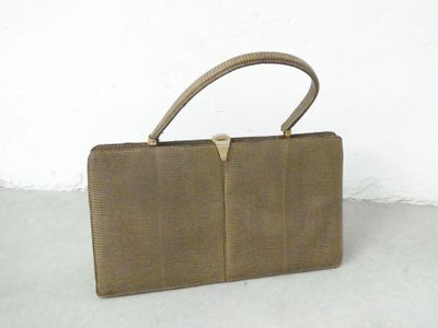 brown leather purse with gold metal handle on cement floor
