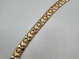 gros plan d'un bracelet en or sur une surface blanche
