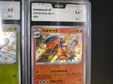 three pokemon cards in plastic cases sitting on a table