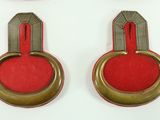 three pairs of red and gold buttons on a white surface
