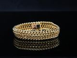 a gold bracelet with a pink stone on a black surface