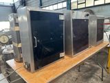 three ovens sitting on a table in a warehouse