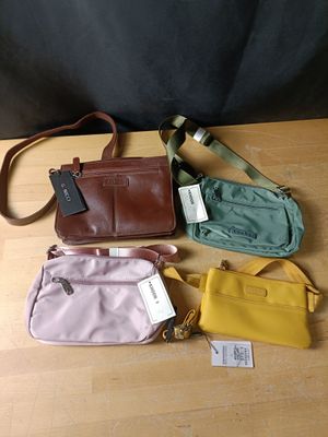 quatre sacs à main posés sur une table en bois, avec des étiquettes accrochées dessus