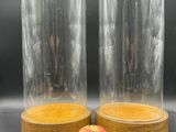 deux cloches en verre avec un socle en bois et une pomme rouge
