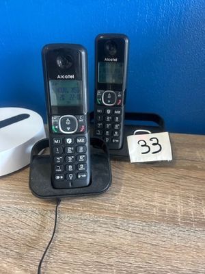 two phones that are sitting on a table next to a charger