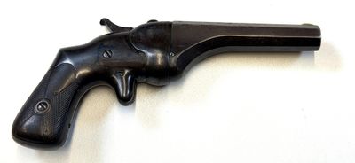 an old black revolver on a white surface with a white background