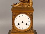 une horloge en or avec une femme assise dessus