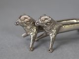 pair of silver sheep figurines sitting on top of each other on a gray surface